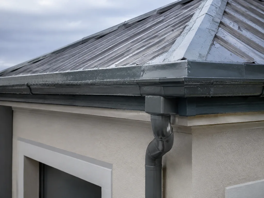 A repaired roof edge and rainwater junction after coastal rain
